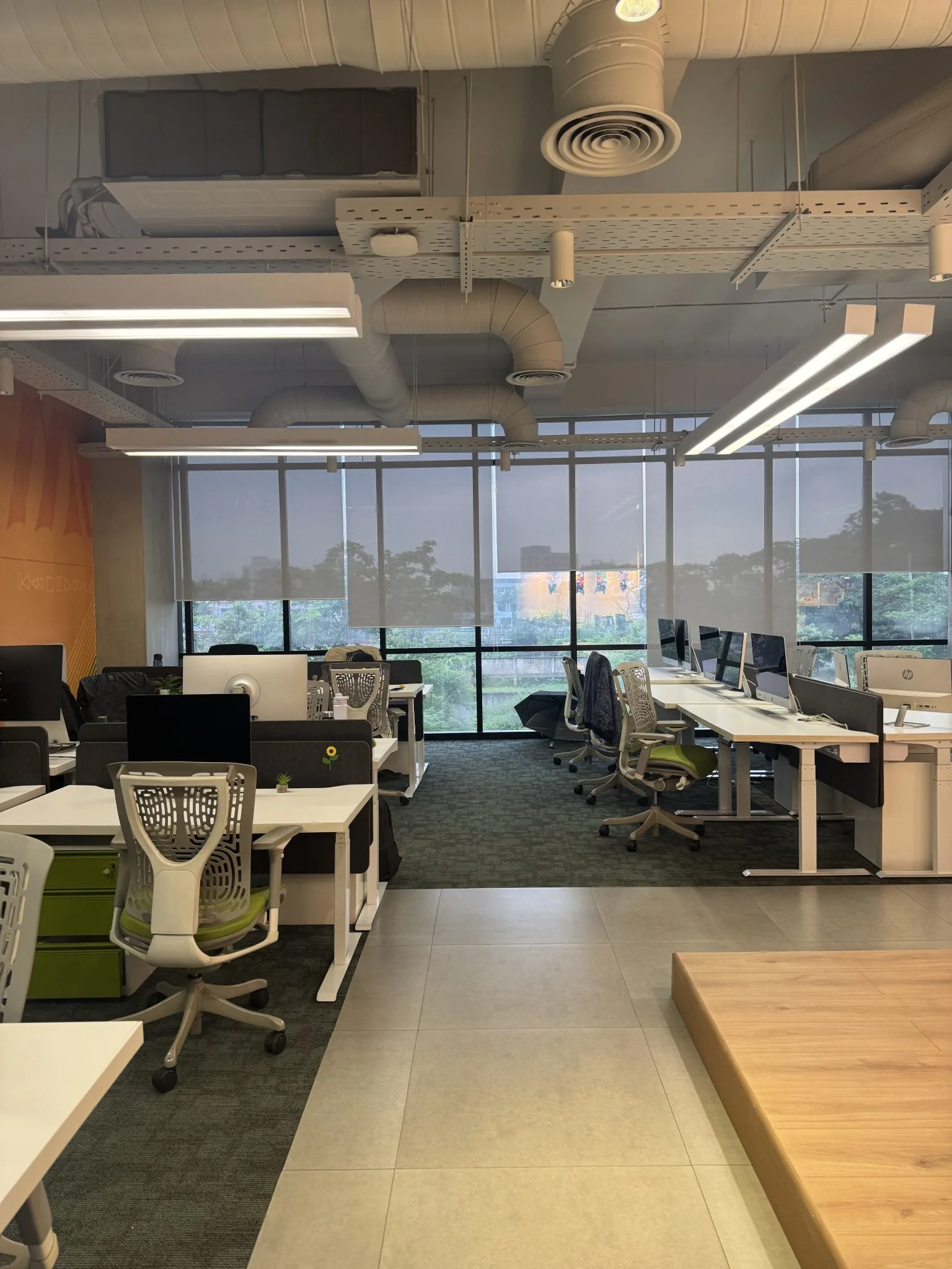 Escritório moderno de plano aberto com estrutura industrial aparente e estações de trabalho.