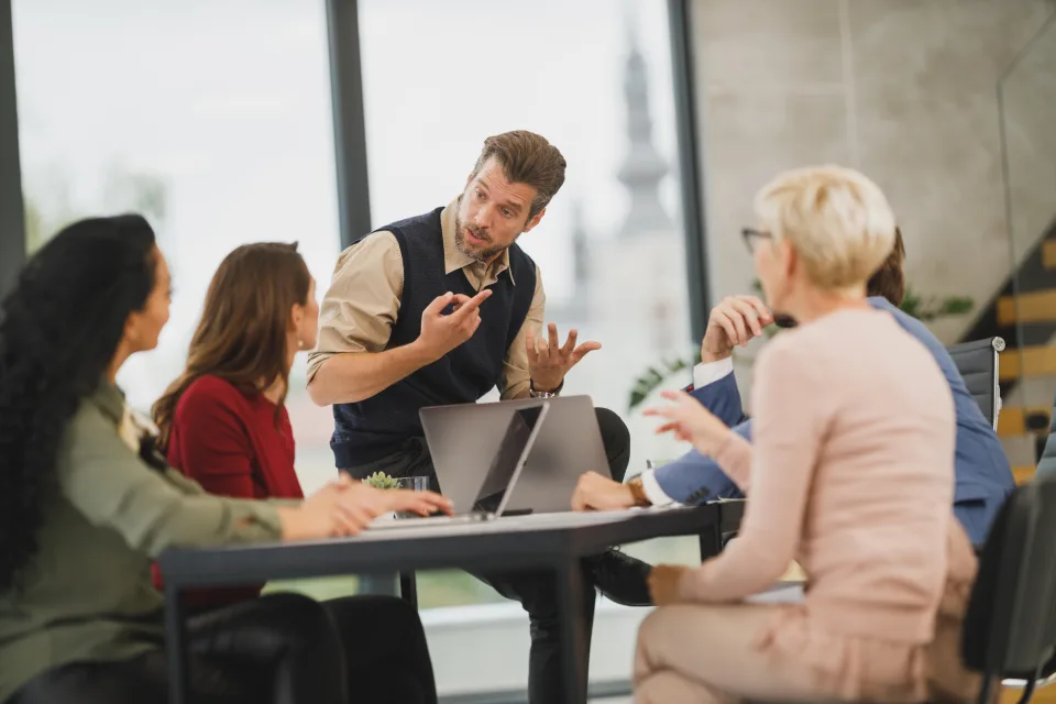 Equipe em reunião de negócios discutindo em torno de uma mesa.