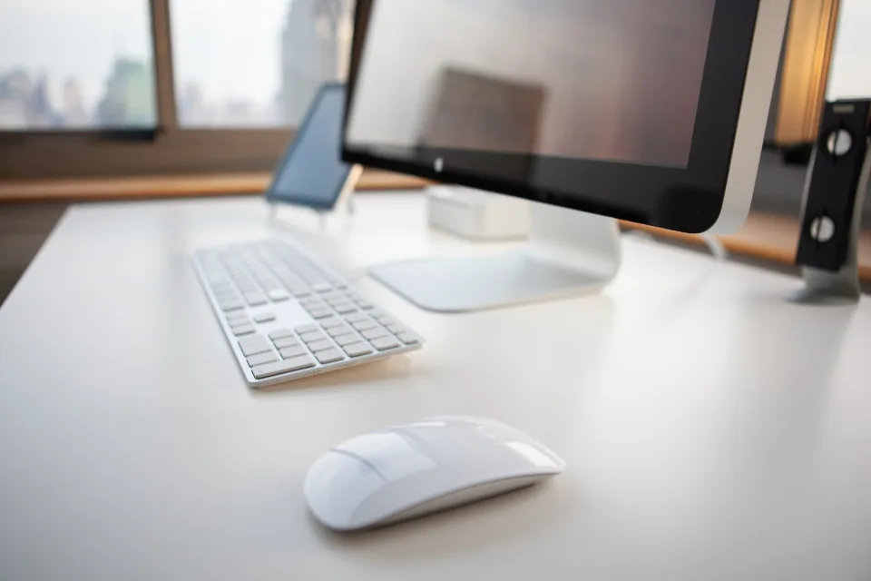 Mesa de trabalho minimalista com teclado, mouse e monitor.